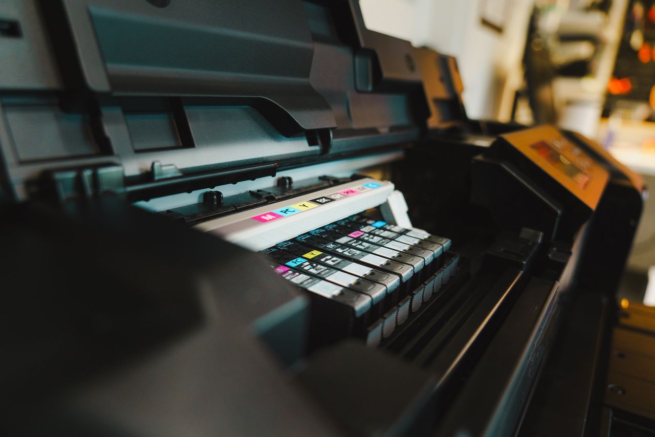 Offerings Detailed view of ink cartridges inside a digital inkjet printer in an office setting.