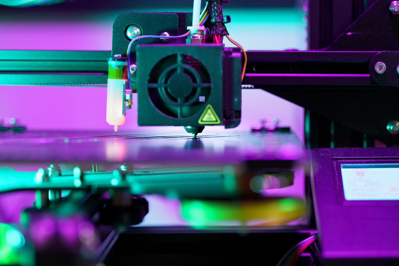 Offerings A neon-lit 3D printer operating, showcasing advanced technology and engineering.